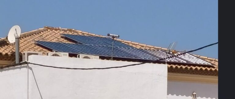 Paneles solares en la cubierta inclinada de una vivienda, vistos desde el patio