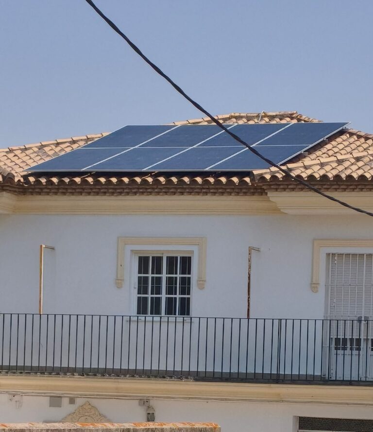 Placas solares en el tejado de una casa señorial de fachada blanca