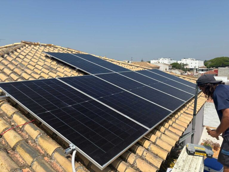 Paneles solares sobre tejado de teja, con el pueblo al fondo