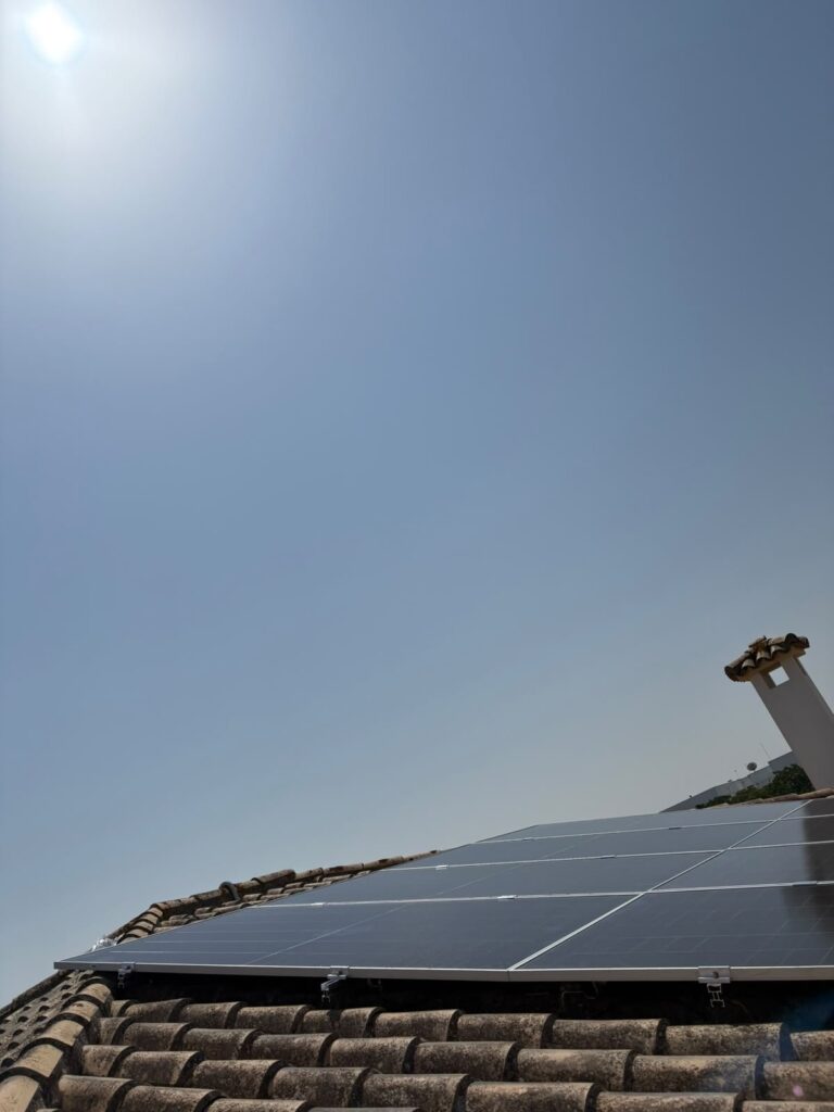 Placas solares en la cumbrera de un tejado, recortadas contra el cielo