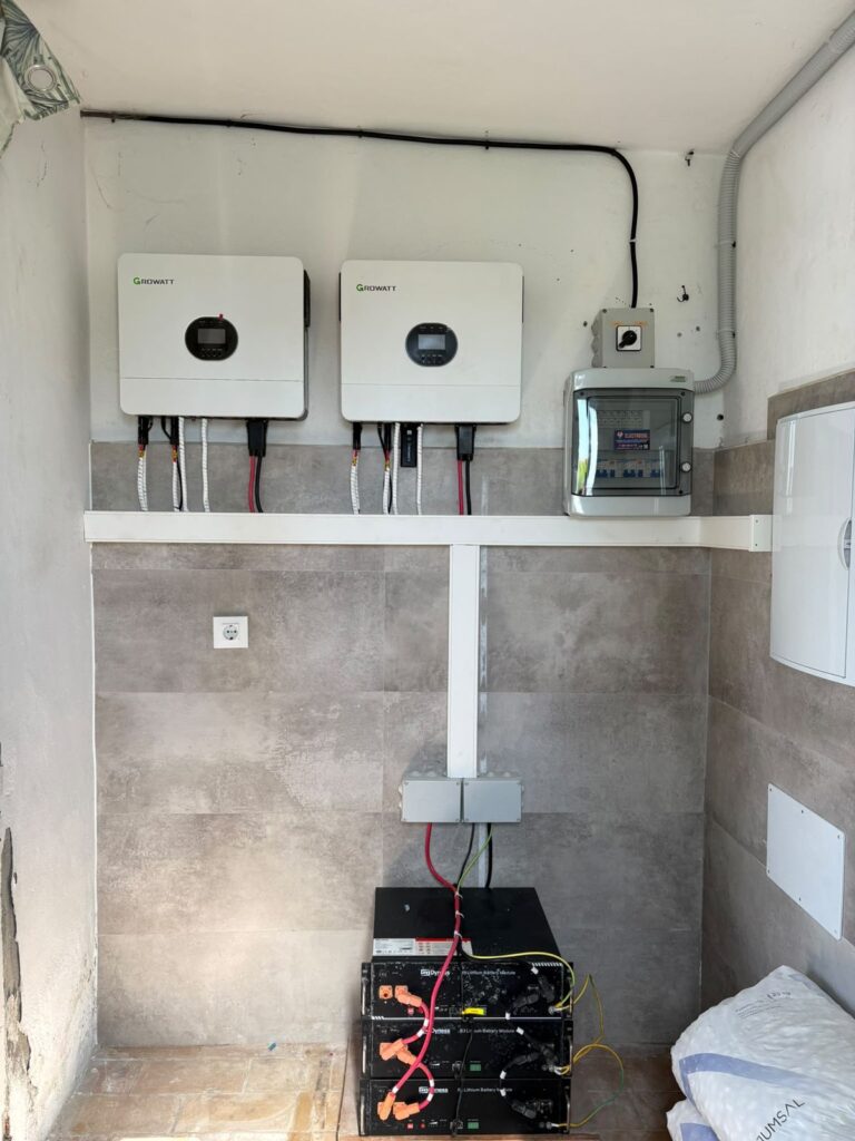 Dos inversores Growatt y batería en la pared de un cuarto técnico alicatado