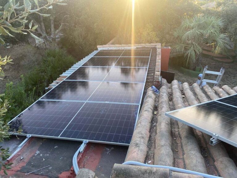 Paneles solares sobre teja junto a un muro, al atardecer