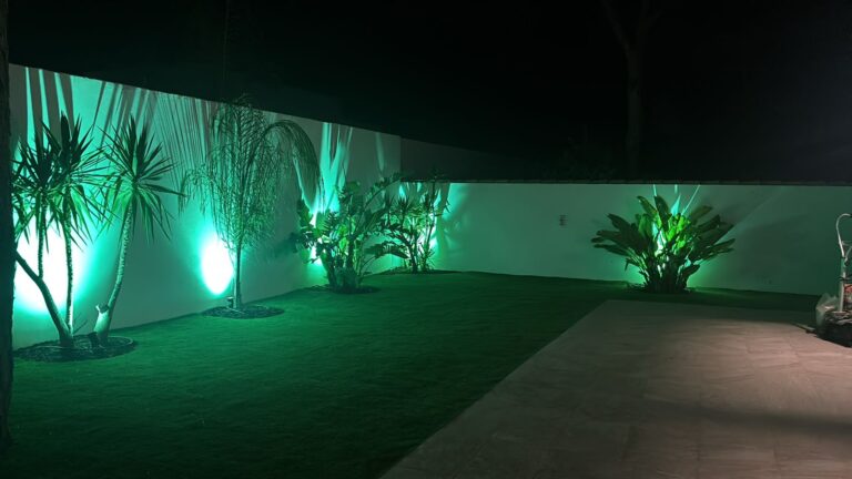 Jardín iluminado de noche con focos verdes